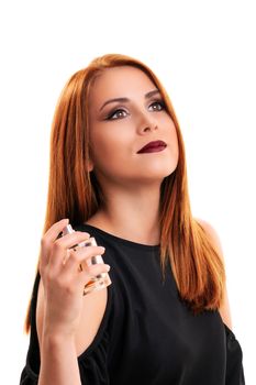 Close up of a beautiful young redheaded woman with elegant make up applying perfume on herself, isolated on white background. Elegant woman enjoying the scent of her perfume.