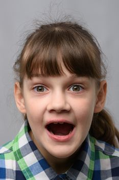 Portrait of a genuinely surprised ten-year-old girl with closed eyes, European appearance, close-up