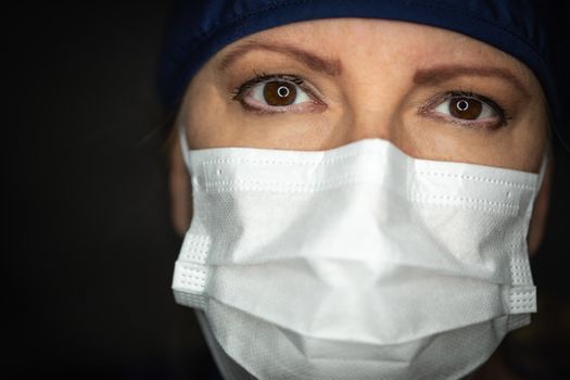 Female Doctor or Nurse Wearing Medical Face Mask on Dark Background.