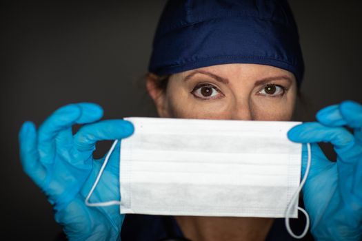 Female Doctor or Nurse Wearing Surgical Gloves Holding Up Medical Face Mask.