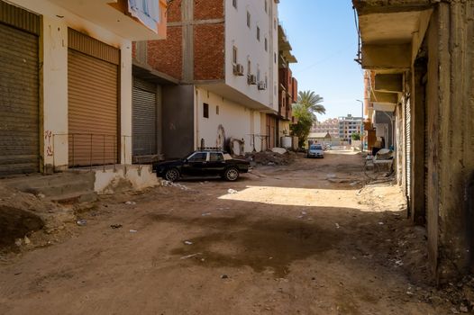 Egypt, Hurghada, dirt street with multi-family houses and old cars
