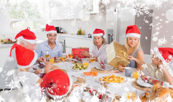 Composite image of a Smiling family around the dinner table at christmas against snow