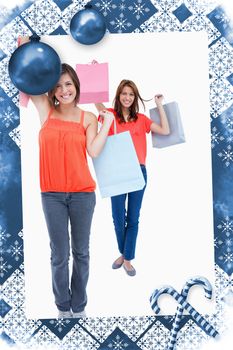 Smiling teenagers holding purchase bags in the air  against christmas frame