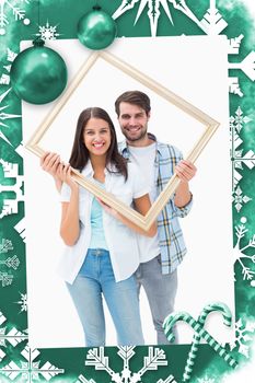 Happy young couple holding picture frame against christmas frame