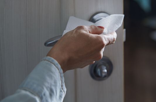 Woman cleaning the door handle with disinfecting wipe