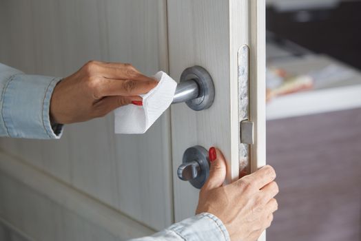 Woman cleaning the door handle with disinfecting wipe