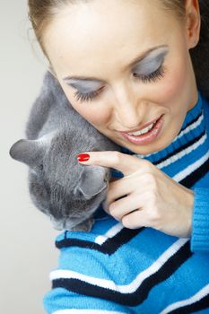 Smiling woman holding and pampering cat indoors