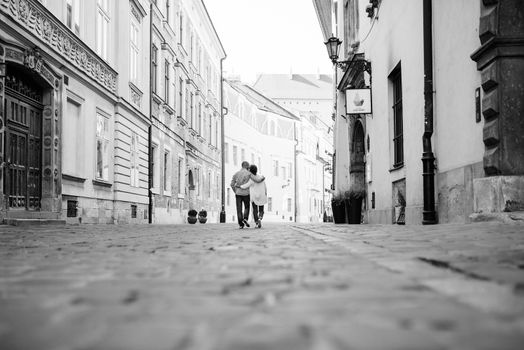 guy and a girl happily walk in the morning on the empty streets of old Europe