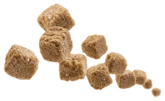 Brown cane sugar levitates on a white background.