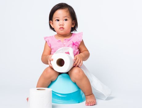 Asian little cute baby child girl education training to sitting on blue chamber pot or potty with toilet paper rolls, studio shot isolated on white background, wc toilet concept