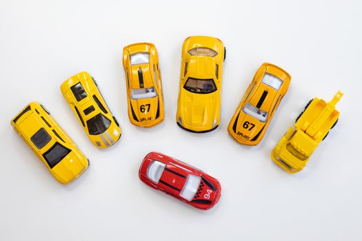 A red car toy surrounded by orange cars