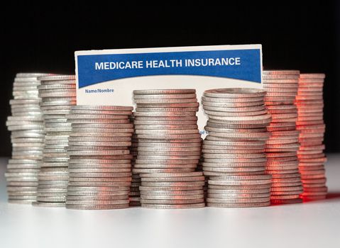 Many stacks of old silver dimes with medicare health insurance card to illustrate budget debt funding issues of the popular program
