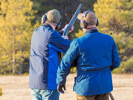 Men practicing of shooting outdoor. Shooting Center in Estonia, Tallinn. Forest on the background. Autumn season