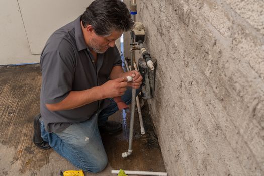 an old man fixing a broken tube of his own house