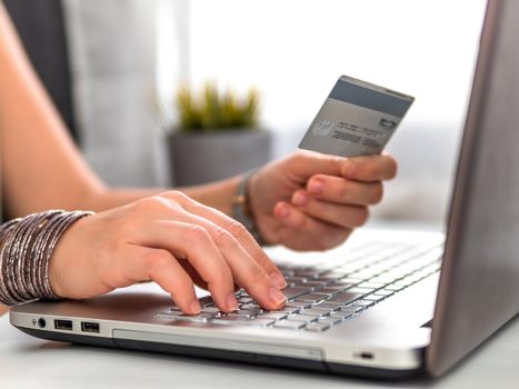 Online shopping concept. Close-up woman's hands holding credit card and using laptop keyboard for online shopping