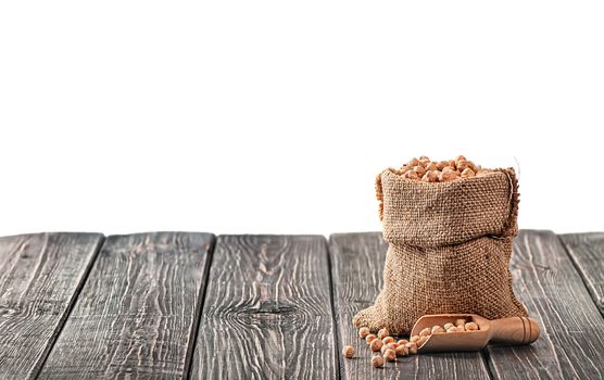 Bag with chickpeas and scoop near on table isolated on white background