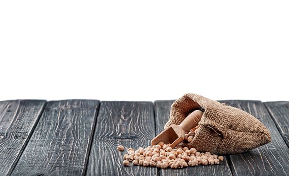 Chickpea spill out of the bag and wooden scoop on table isolated on white background