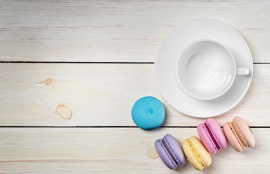 Macaroons and empty cup top view on wooden table