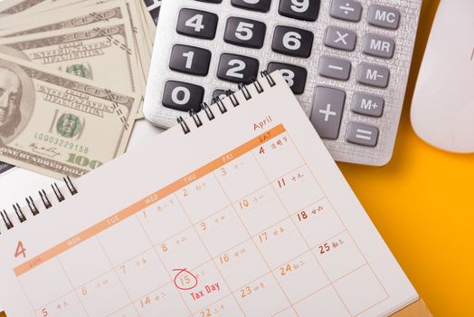 April of the year is Tax Day, Top view flat lay closeup calculator, laptop computer, calendar, and Dollar money, on yellow background business finance budget concept with copy space for text