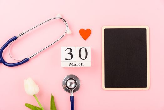 Doctor's Day concept, flat lay top view, equipment medical red heart stethoscope on pink background, care patient in hospital with black board copy space for text