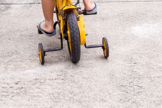 Children with slippers cycling bike with training wheels to prevent falls