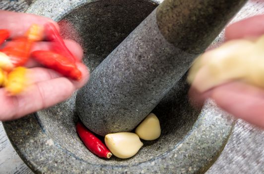 Pepper and garlic are put into a stone mortar to pound