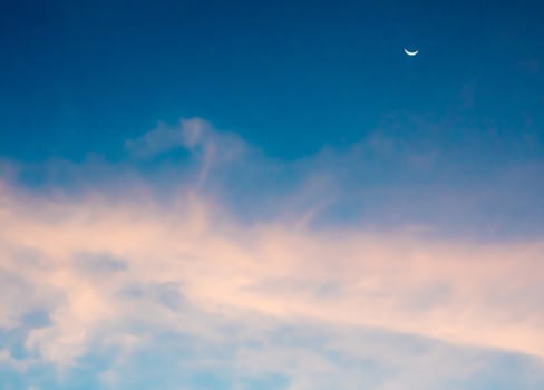 Crescent moon and fluffy purple clouds in the sky