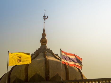 Thai flag and the flag of the king in front of the mosque building with evening sky