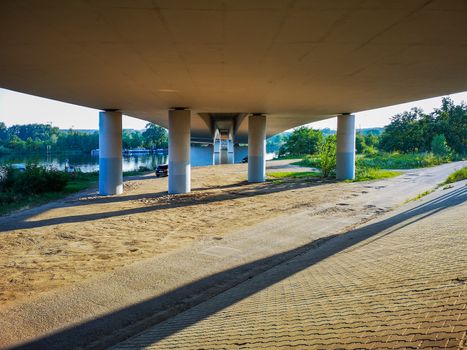 Concrete pillars under bridge on beach near river