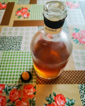 Half full Bottle of whisky and plug on colorful oilcloth