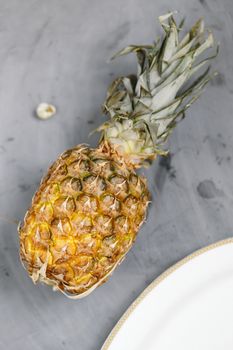 White Plate with Ripe Whole Pineapple on Grey Concrete Background