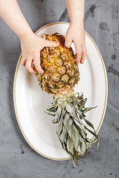 White Plate with Ripe Whole Pineapple on Grey Concrete Background