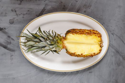 White Plate with Ripe Sliced Pineapple on Grey Concrete Background