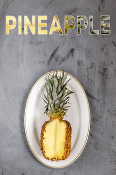 White Plate with Ripe Sliced Pineapple on Grey Concrete Background. Word Pineapple