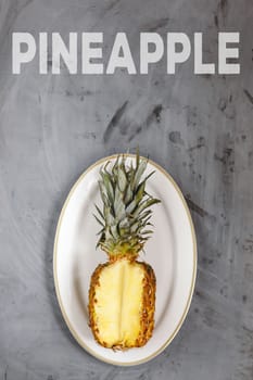 White Plate with Ripe Sliced Pineapple on Grey Concrete Background. Word Pineapple