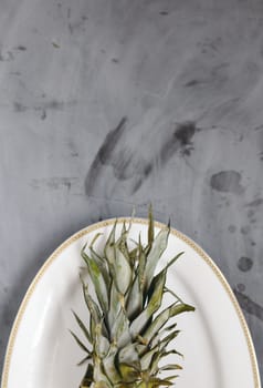 White Plate with Ripe Sliced Pineapple on Grey Concrete Background. Copyspace.