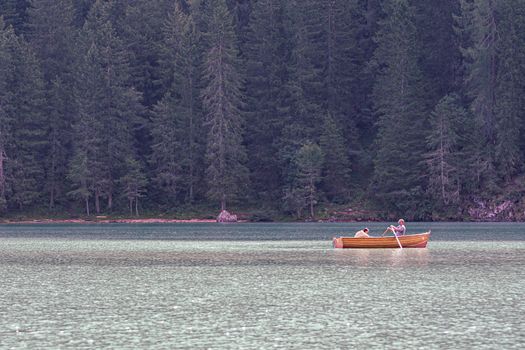 Tourists paddle on a wooden boat on Lake Braies, Trentino Alto Adige