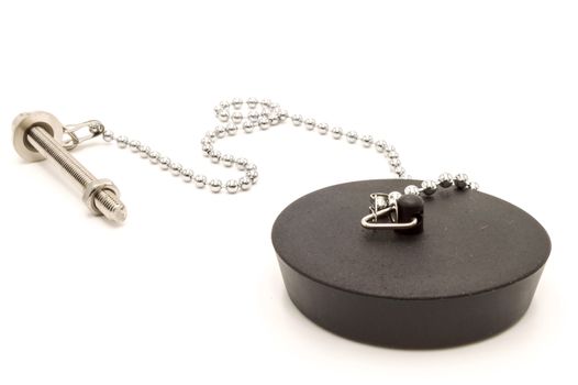 Black rubber sink stopper with chain and chrome screw on white background.