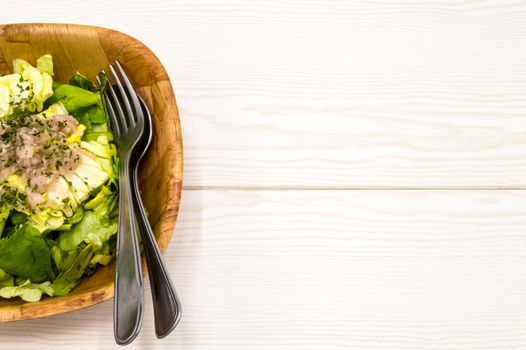 fresh green lettuce salad in a bowl isolated on a white wooden background.