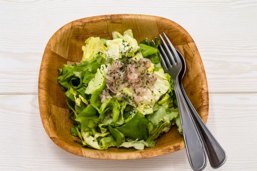 fresh green lettuce salad in a bowl isolated on a white wooden background.