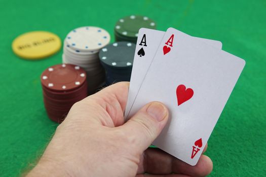 A hand holding a pair of aces with casino chips in background Texas holdem poker best pocket rockets american airlines