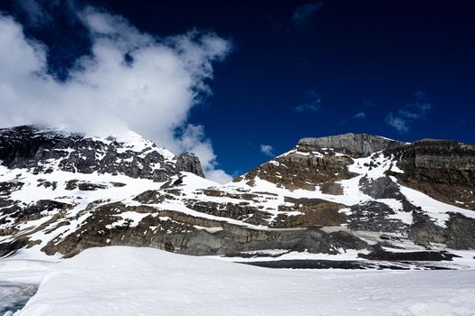 Rocky Mountain filled with ice and snow contrasting a bright blue sky