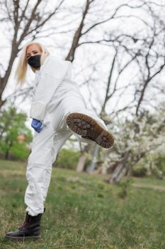 Woman in black mask, white protective suit with leg up