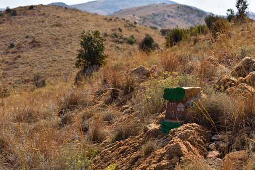 Hiking trail route marker on a hill in mountainous grassland terrain, Rustenburg, South Africa