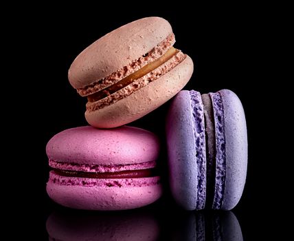 Heap of colorful macaroons on black background