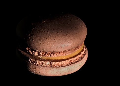 One beige macaroon on black background darkened