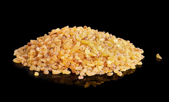 Pile of dry bulgur groats on black background