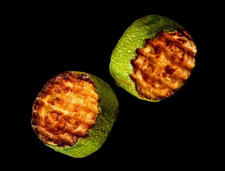 Two slices of zucchini grill on a black background rotated