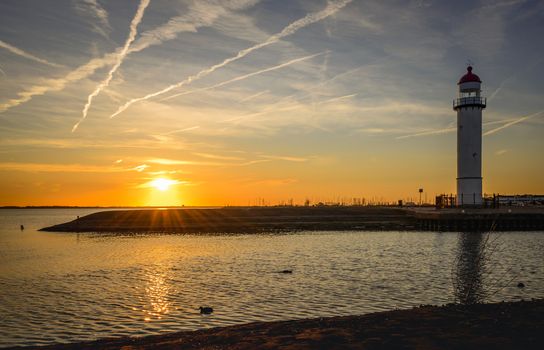 the lighthouse of hellevoetsluis in the sunset on the haringvliet, with red sunlight over the harbour