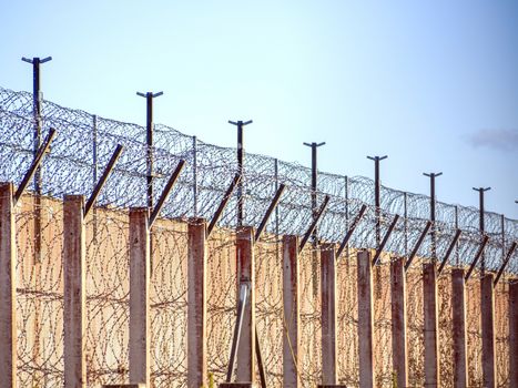 Restricted Area Barbed Fence. Concrete wall, against the backdrop of barbed wire, the concept of prison, salvation, Refugee, lonely, space for text. Protected object, no unauthorized entry.